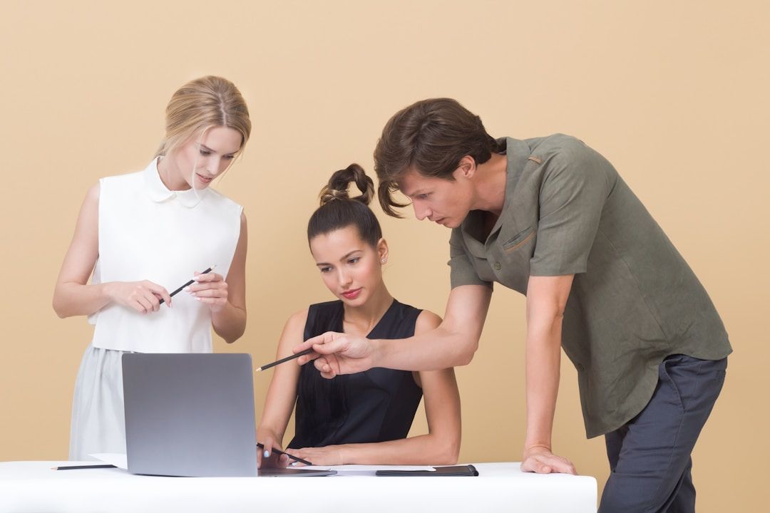 Three colleagues collaborating on a laptop, discussing the impact of AI enterprise search on productivity and teamwork.