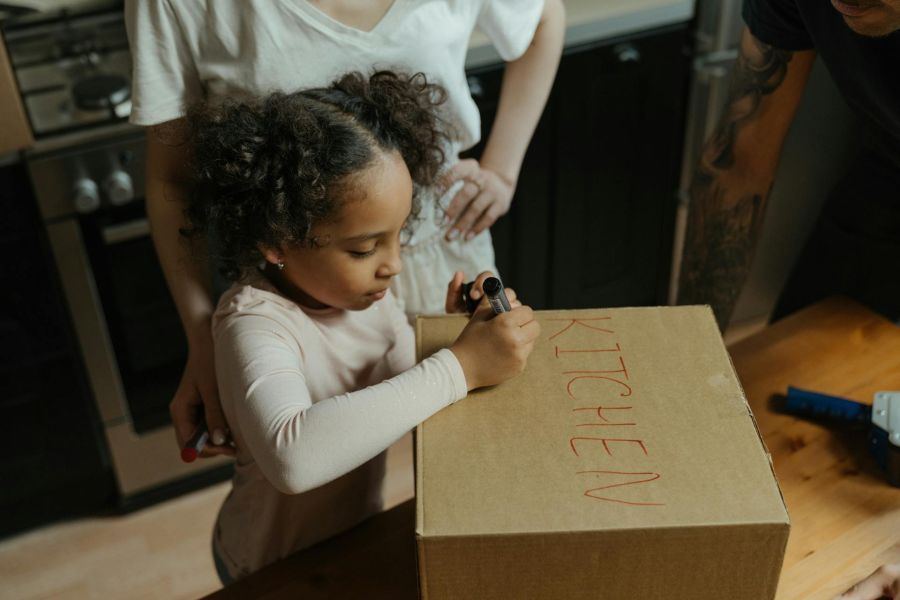 girl labeling moving boxes with red marker