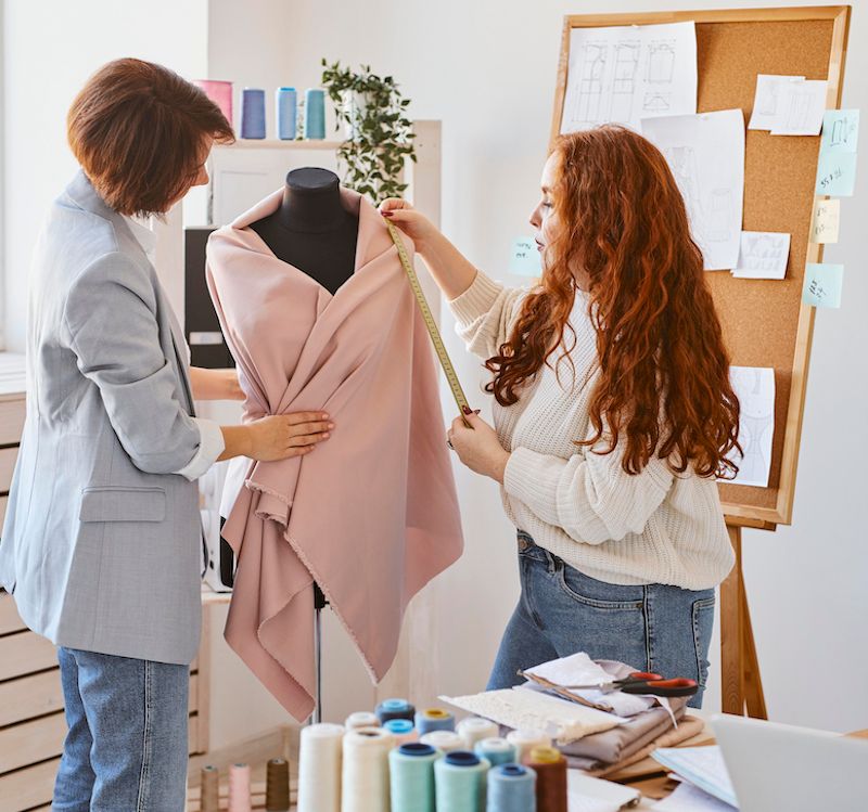 female-fashion-designers-working-atelier-checking-garment-dress-form.jpg