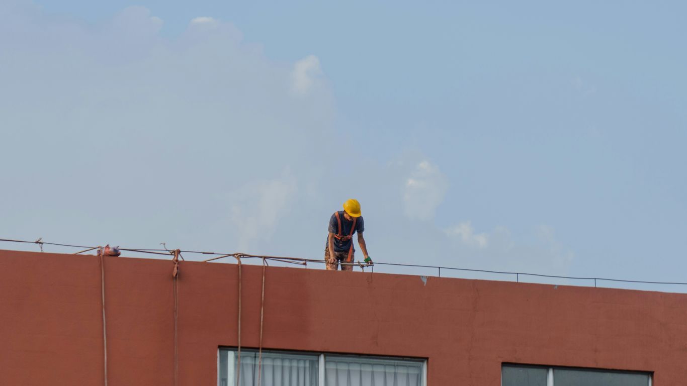 Worker in yellow hard hat on building roof