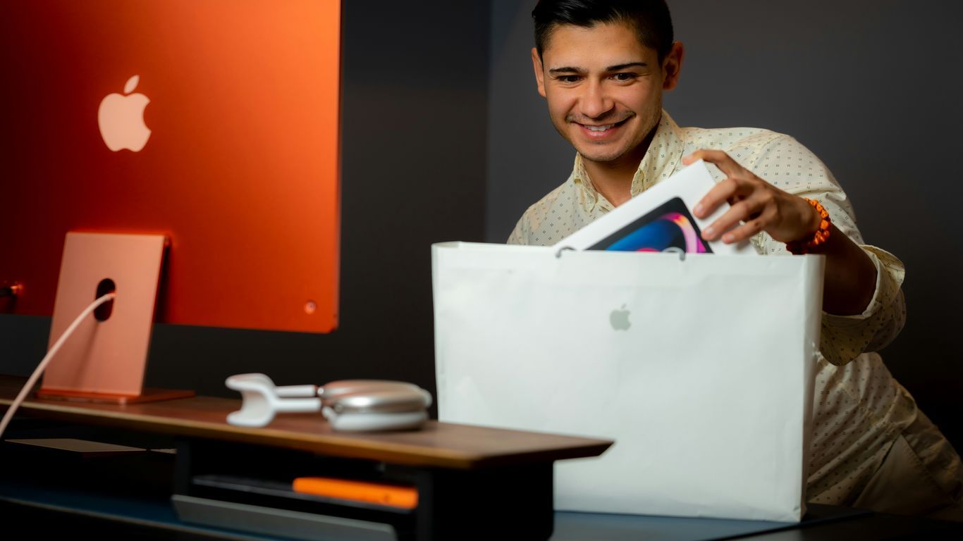 a man sitting at a desk with a bag and a computer