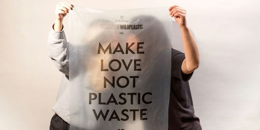 two people holding a sign that says make love not plastic waste