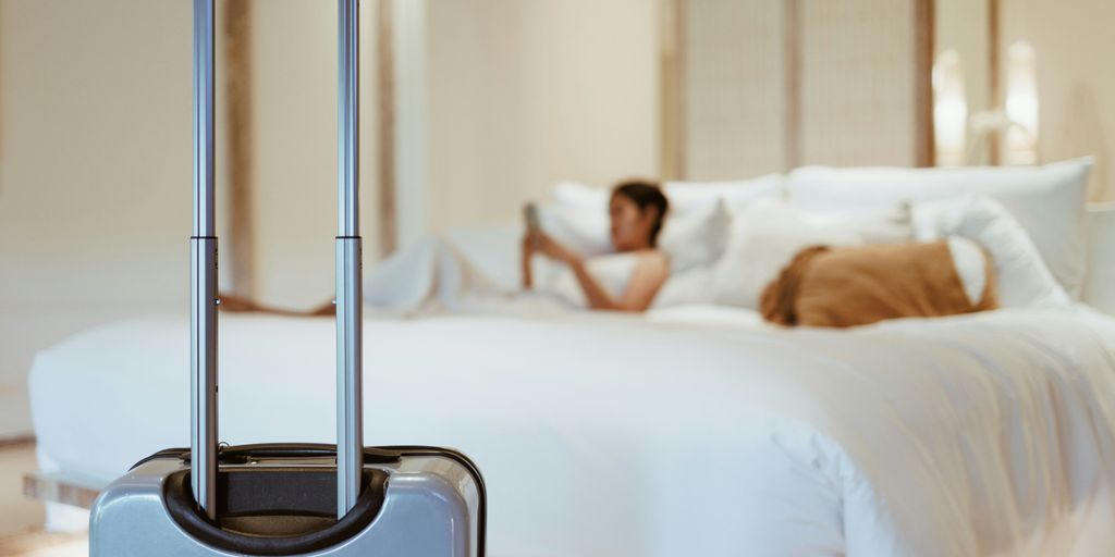 a woman laying on a bed with a suitcase in front of her