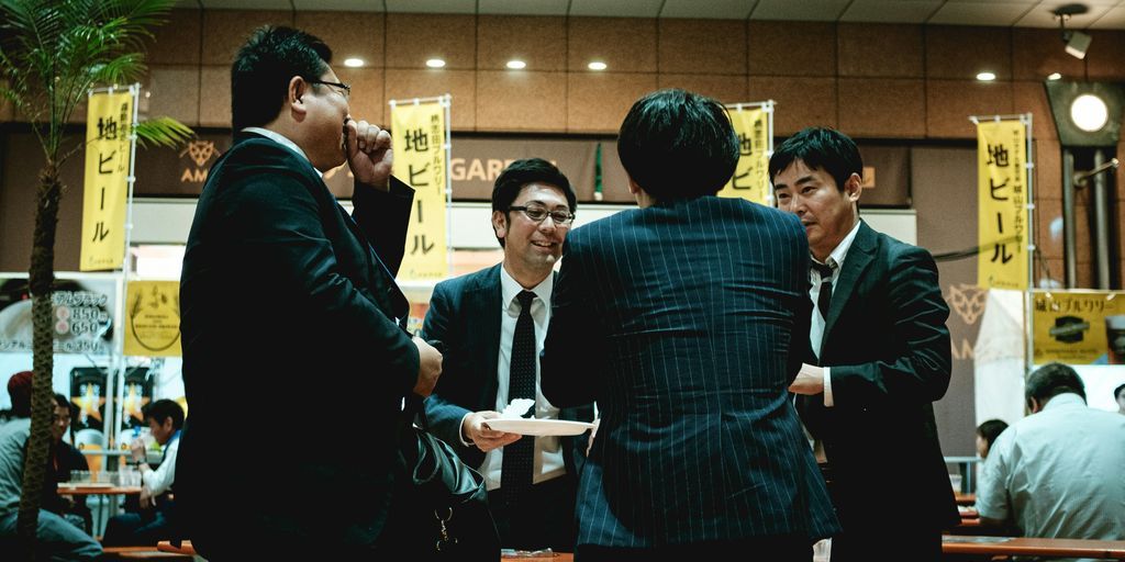 group of people standing in front of brown wooden table