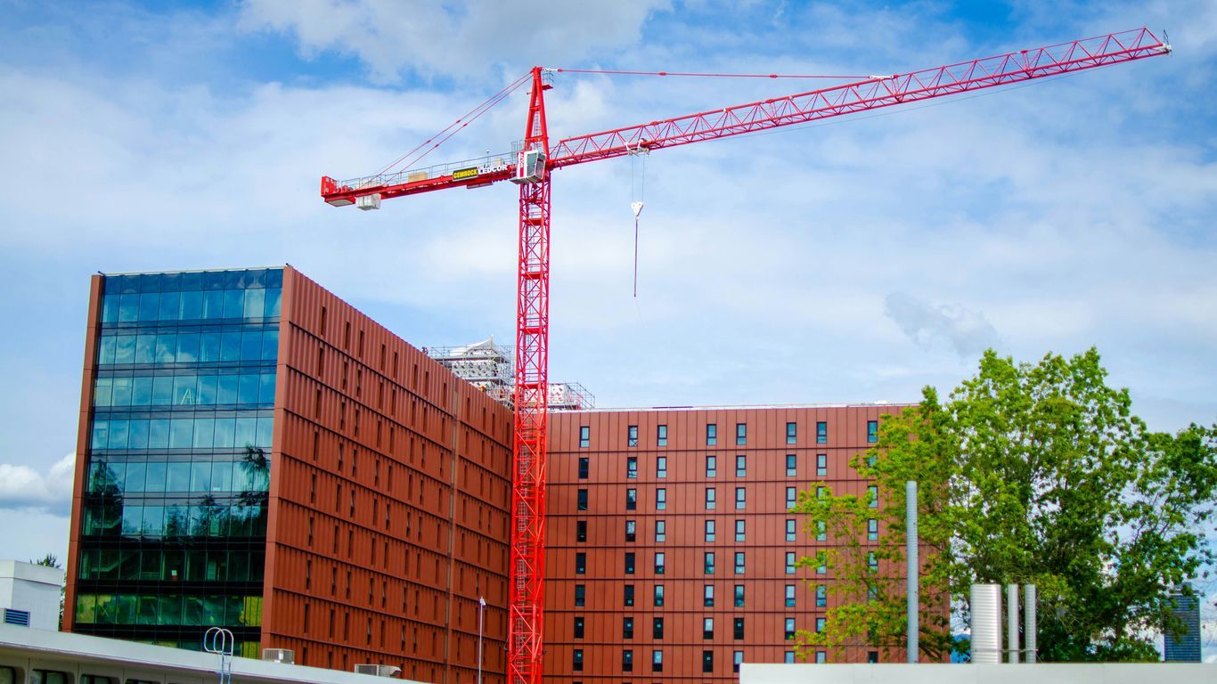 A crane is standing in front of a building under construction