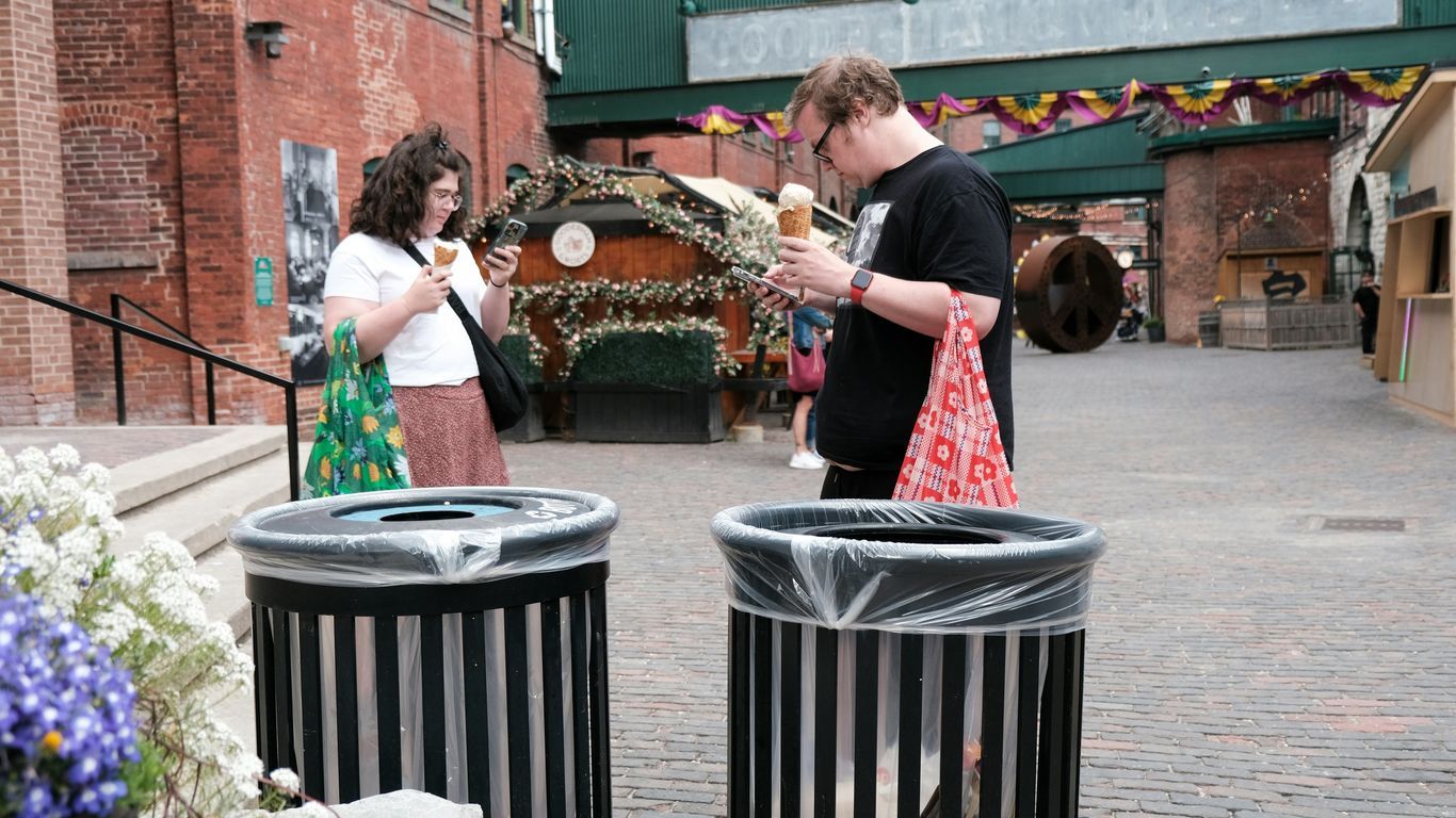 A couple of people standing next to trash cans