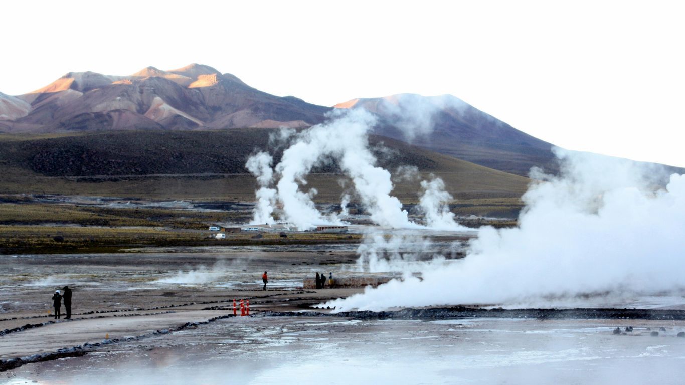 a group of people standing in front of a geyser