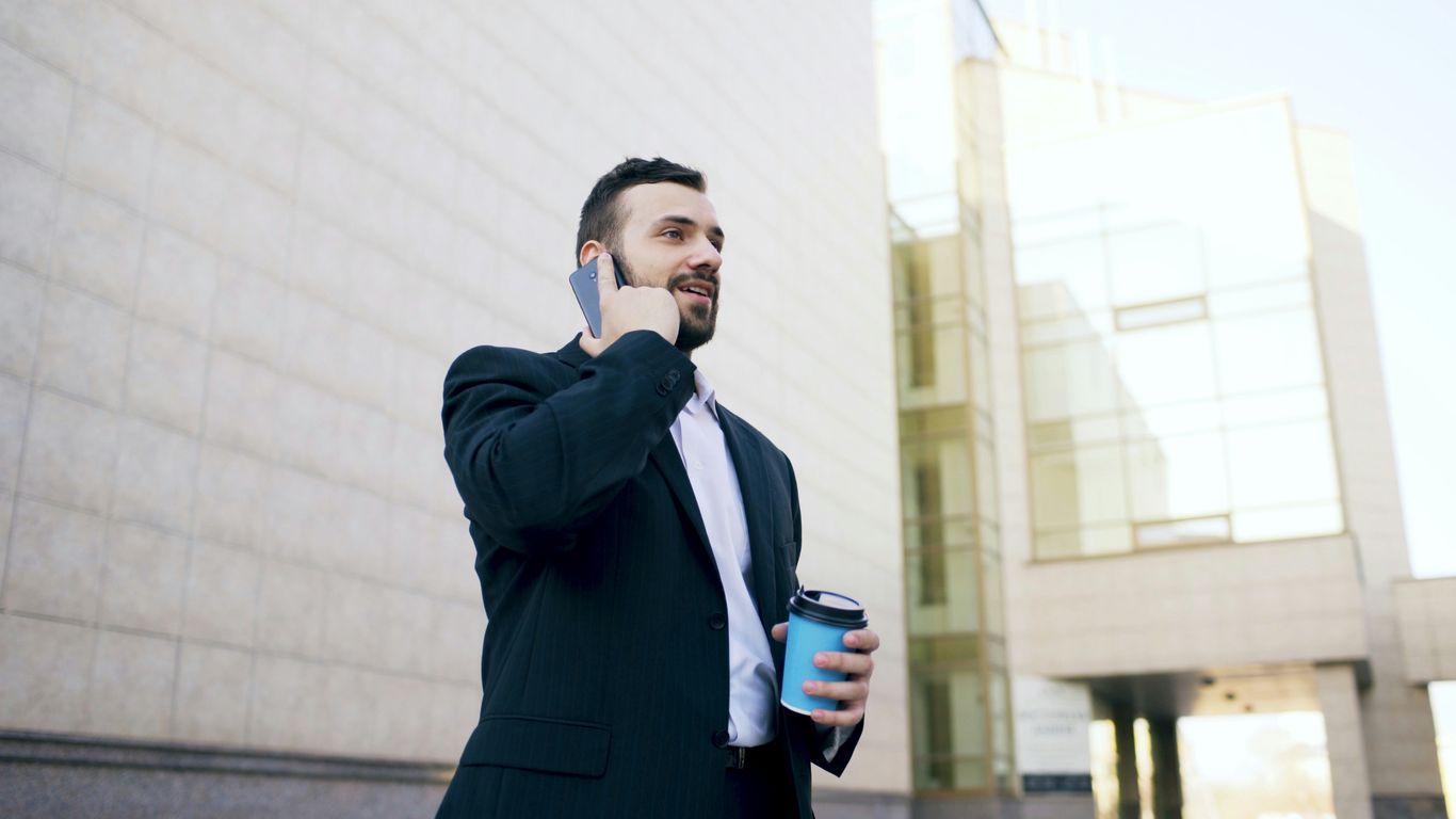 Man in suit talking on phone with coffee cup