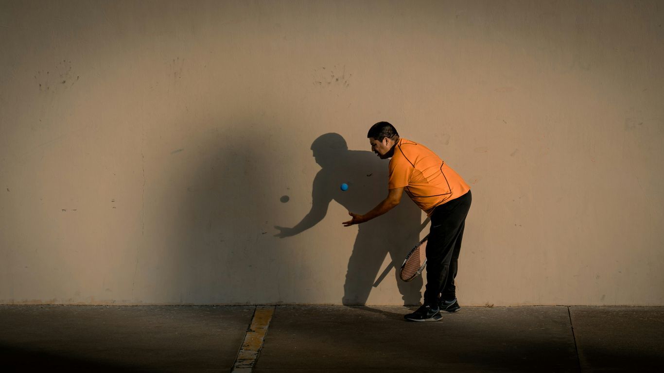 a man holding a tennis racquet on top of a tennis court