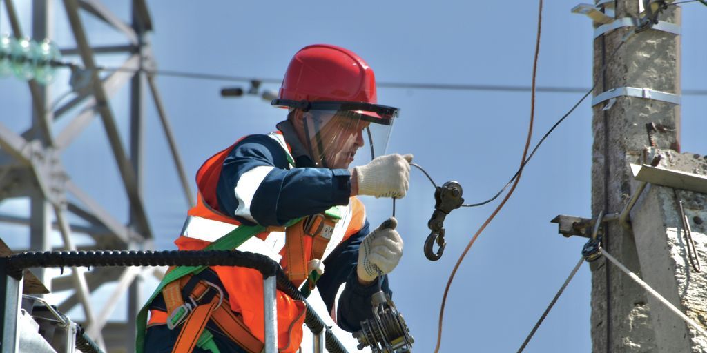 a man in safety gear working on a power pole