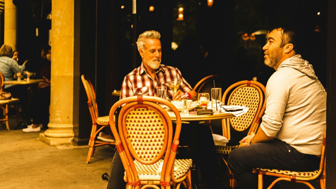 man in red and white plaid dress shirt sitting on brown wooden chair