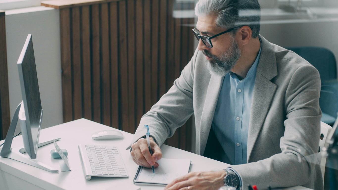 A man sitting at a desk writing on a piece of paper