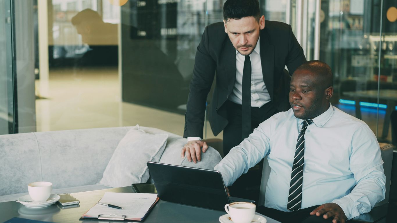 Two businessmen collaborating on a laptop in an office.