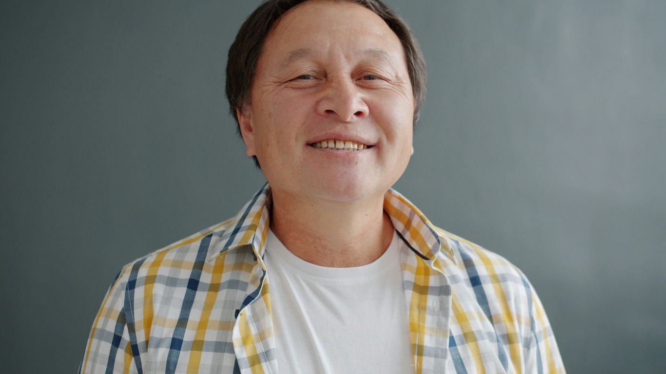 Smiling man in plaid shirt against gray background