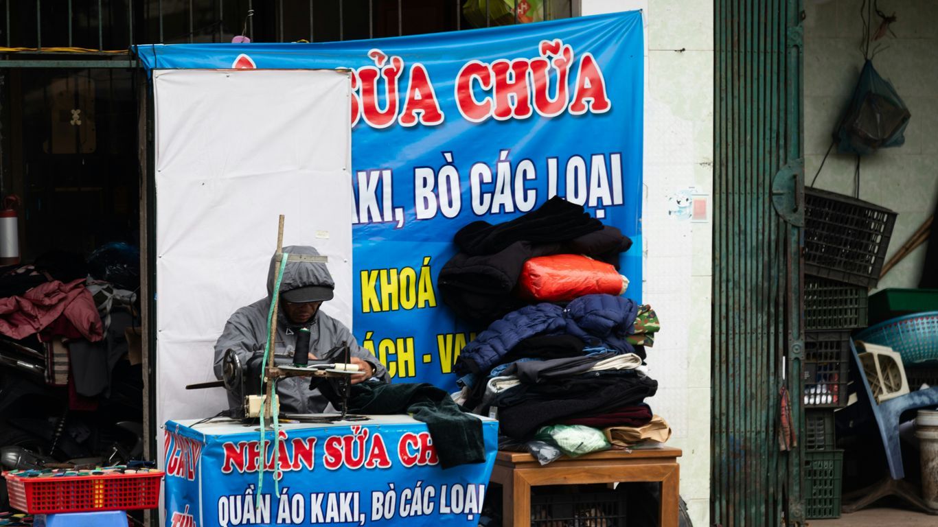 Person sewing clothes at a street stall