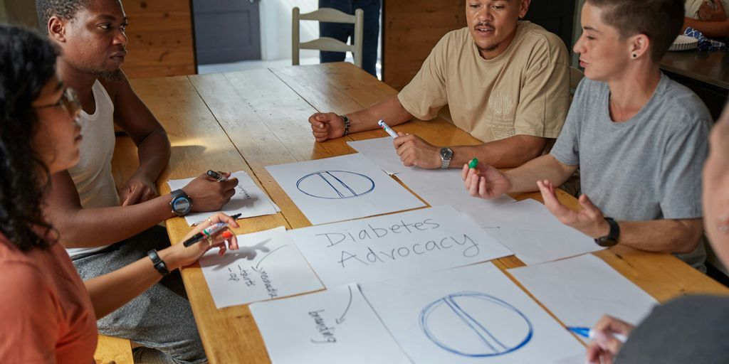People collaborate on diabetes advocacy designs at a table.