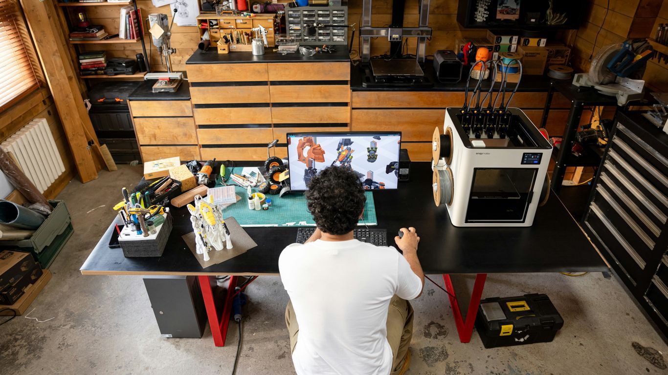 Man working at a desk with 3D printer.