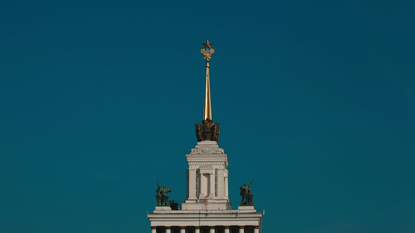 a tall white tower with a gold statue on top