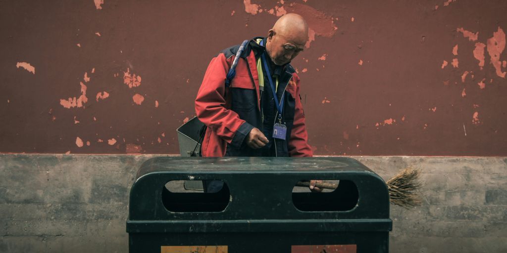 man standing beside trash biin