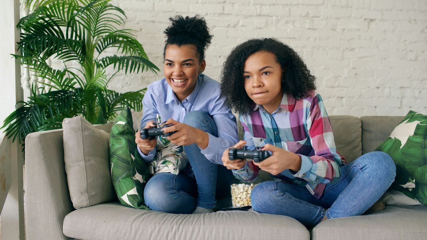 Two women playing video games on a couch.
