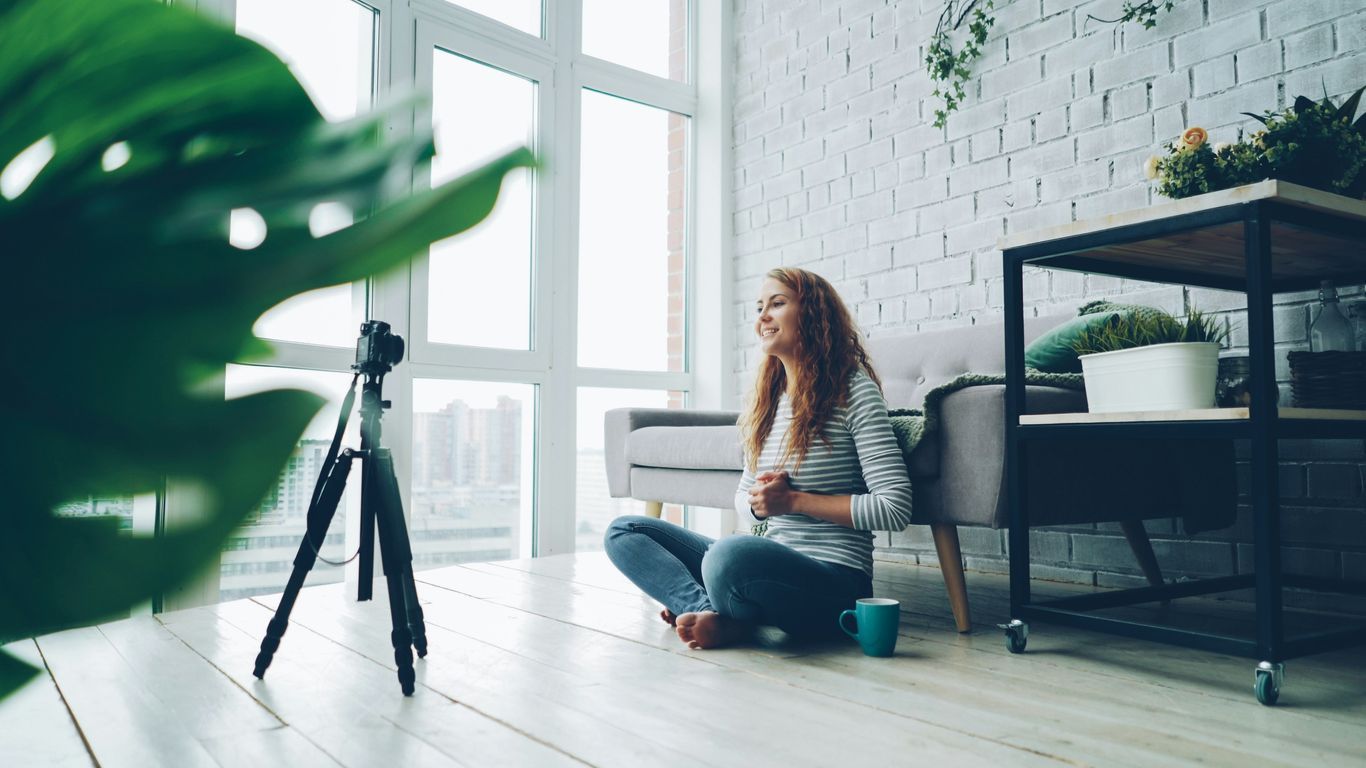 Woman sitting on floor recording with camera.