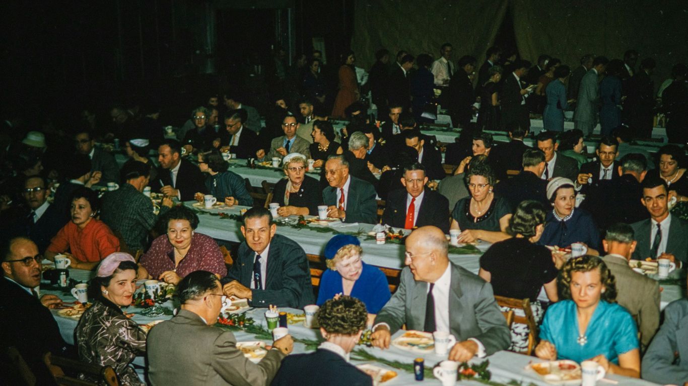 a large group of people sitting at tables eating food