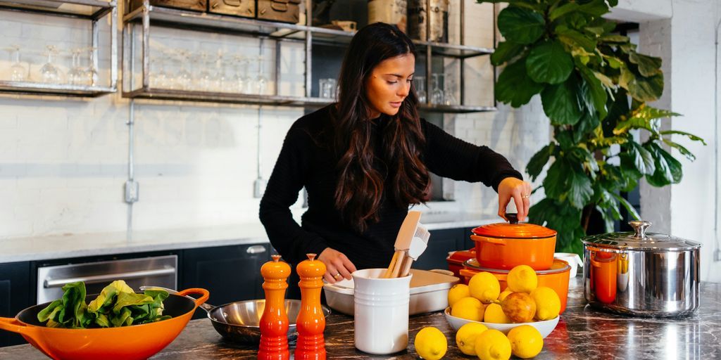 woman standing in front of fruits holding pot's lid