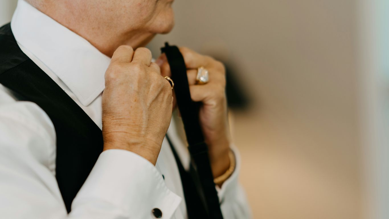 an older woman adjusting her tie in a room