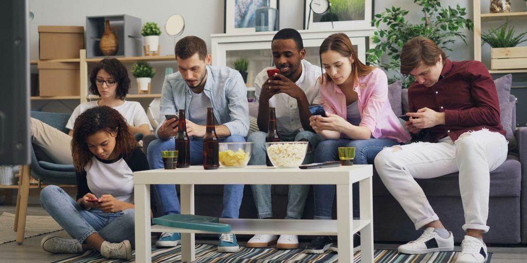 a group of people sitting on a couch looking at their phones