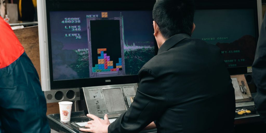 A man plays tetris on a vintage arcade game.