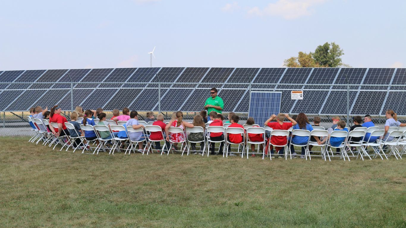 a group of people sitting in chairs in front of a solar panel