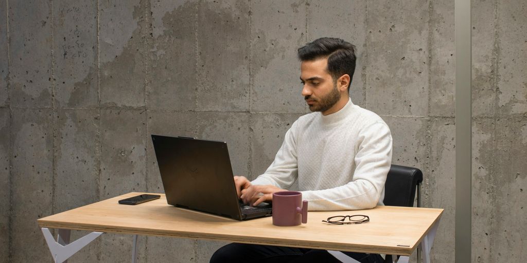 a man sitting at a table using a laptop computer